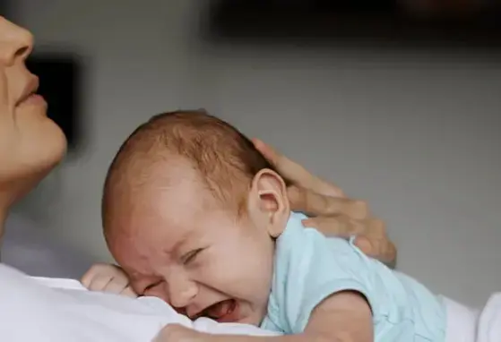 Madre recostada con su hijo llorando en sus brazos