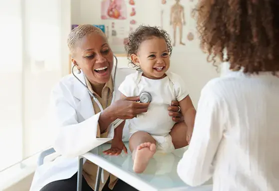 Una doctora examina a un bebé frente a su madre.