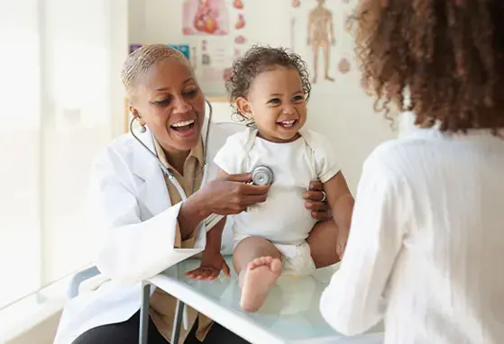 La salud infantil está relacionada con la leche materna. Una doctora examina a un bebé frente a su madre.