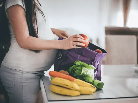 Embarazada sacando frutas y verduras