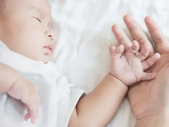 Una madre sostiene la mano de su hijo lactante. 